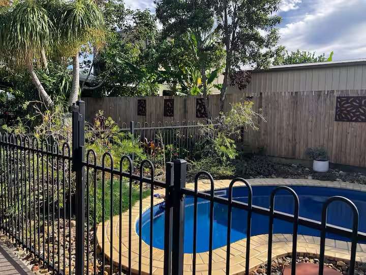 Private circular blue pool surrounded by palms and a timber fence